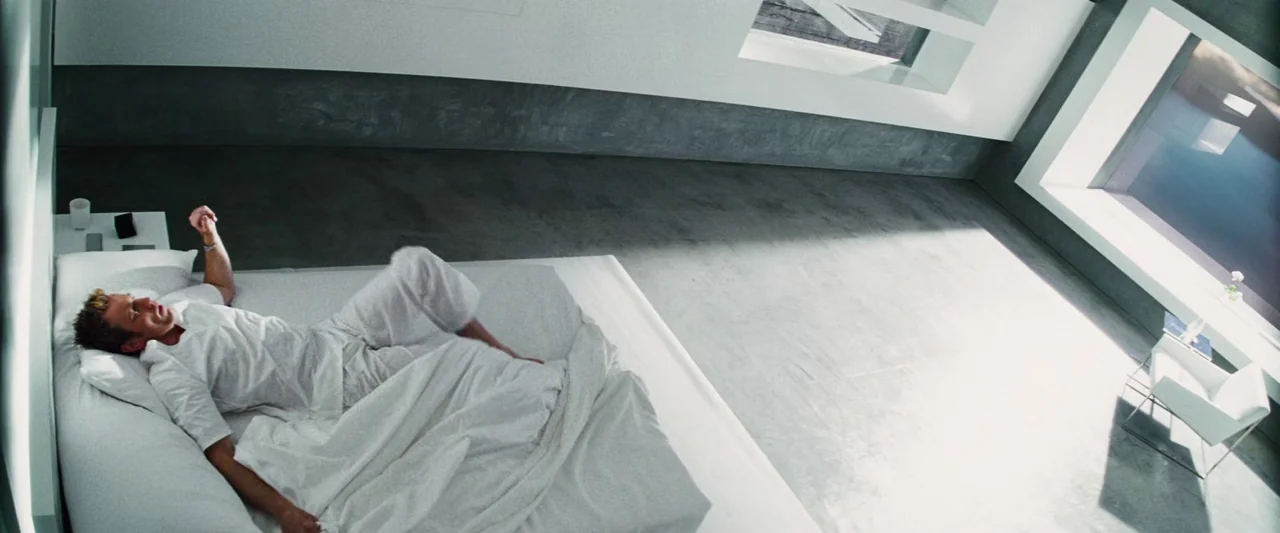 The Island (2005) movie still: wide — A minimalist white room features grey concrete floors and a large rectangular window view. A man in white…