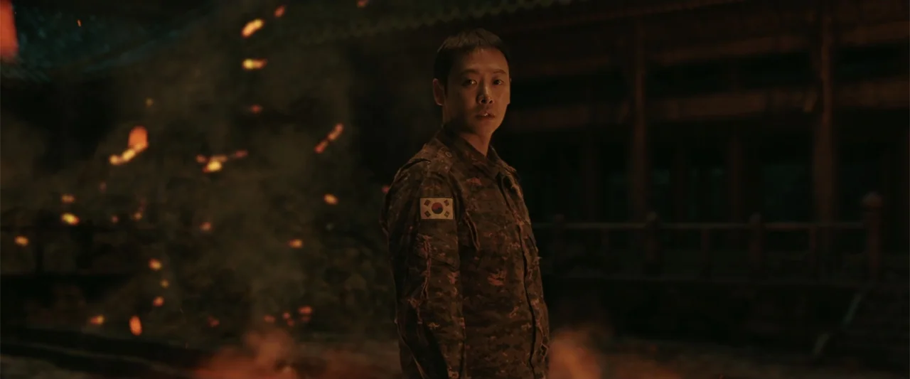 Along with the Gods: The Last 49 Days (2018) movie still: medium — A dark outdoor space features a traditional wooden structure visible in the…