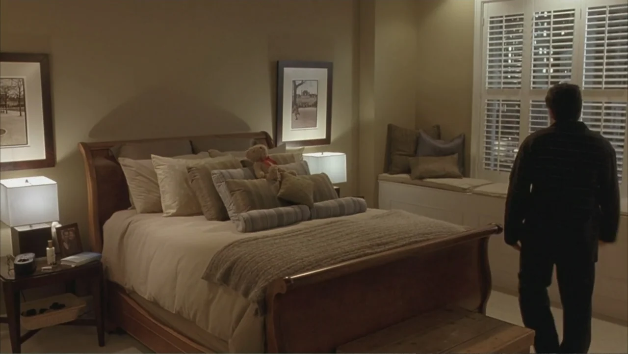 Along Came Polly (2004) movie still: medium — A luxury hotel room features a large bed with multiple pillows and nightstands. A man stands at the…