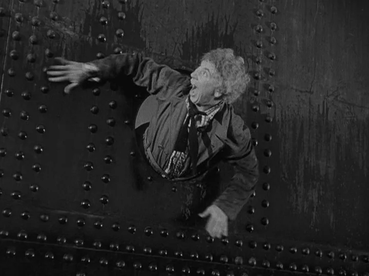 A Night at the Opera (1935) movie still: medium — A heavy iron surface covered with symmetrical rivets features a circular porthole-style opening.…