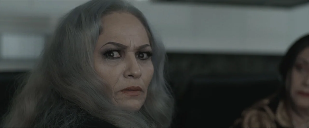 Los habitantes (2023) movie still: closeup — A dimly lit indoor space with neutral-colored walls provides the background for the subjects. A…