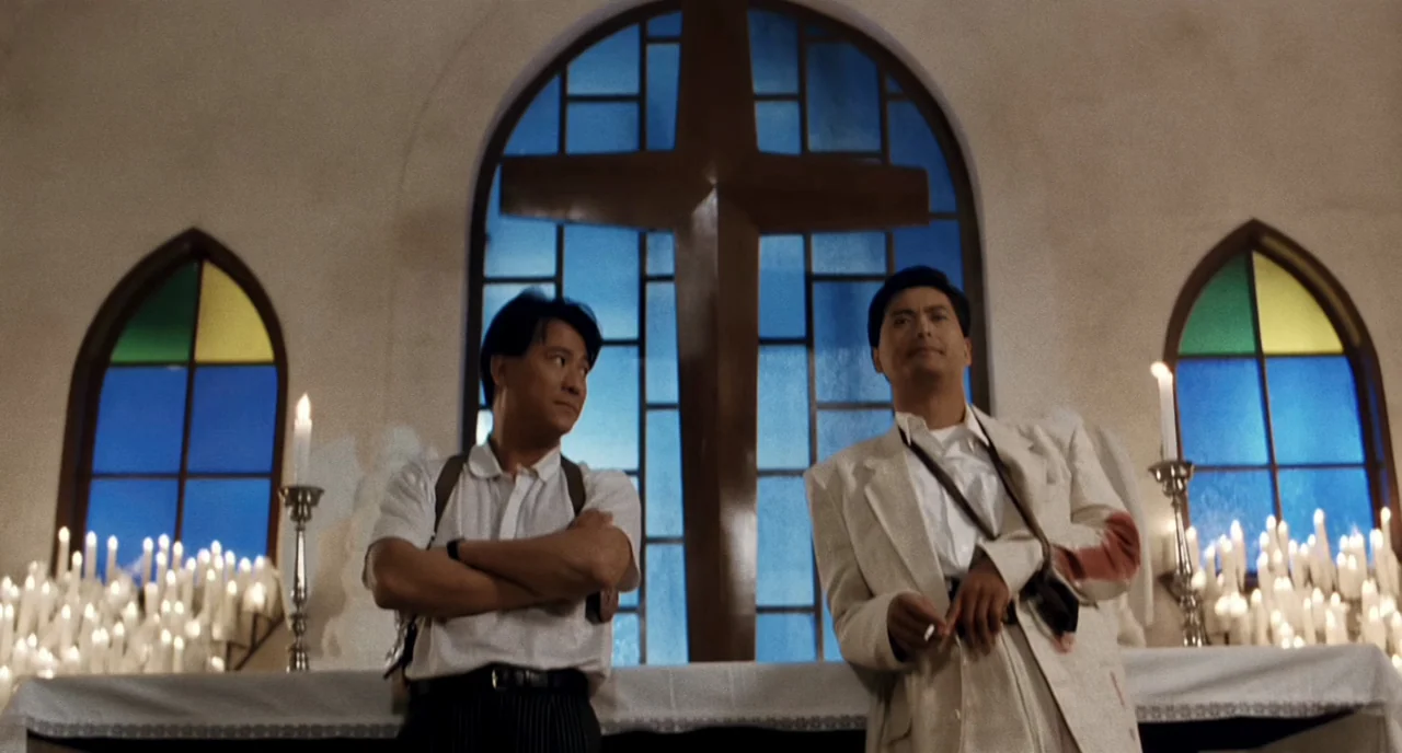 The Killer (1989) movie still: medium — A church altar features a large arched window with a central cross shape above. Two men in formal attire…