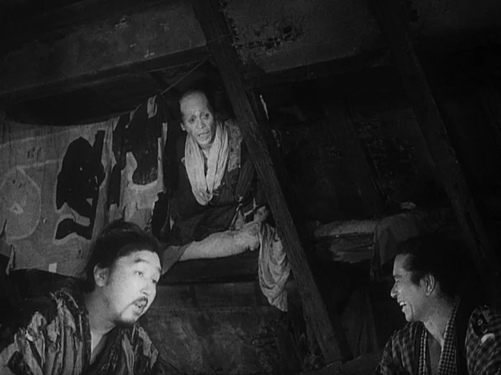 The Lower Depths (1957) movie still: medium — A dark, cramped attic space is constructed of raw timber beams and wooden walls. Three men sit among…