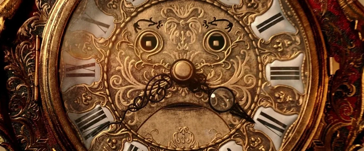 Beauty and the Beast (2017) movie still: closeup — An ornate vintage wall clock features intricate gold filigree work on its central face. Roman…
