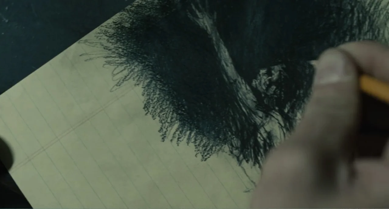 Bad Boys: A True Story (2003) movie still: closeup — A yellow lined legal pad lies on a dark surface under soft light. A hand holds a wooden pencil…
