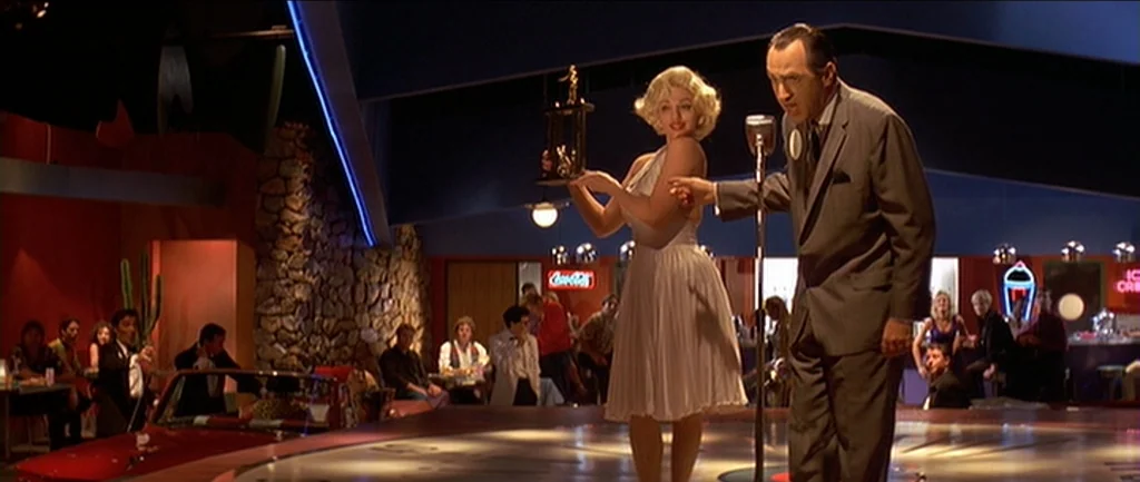 Pulp Fiction (1994) movie still: fullbody — A 1950s-style restaurant features stone walls and blue angular roof architecture with a car parked…