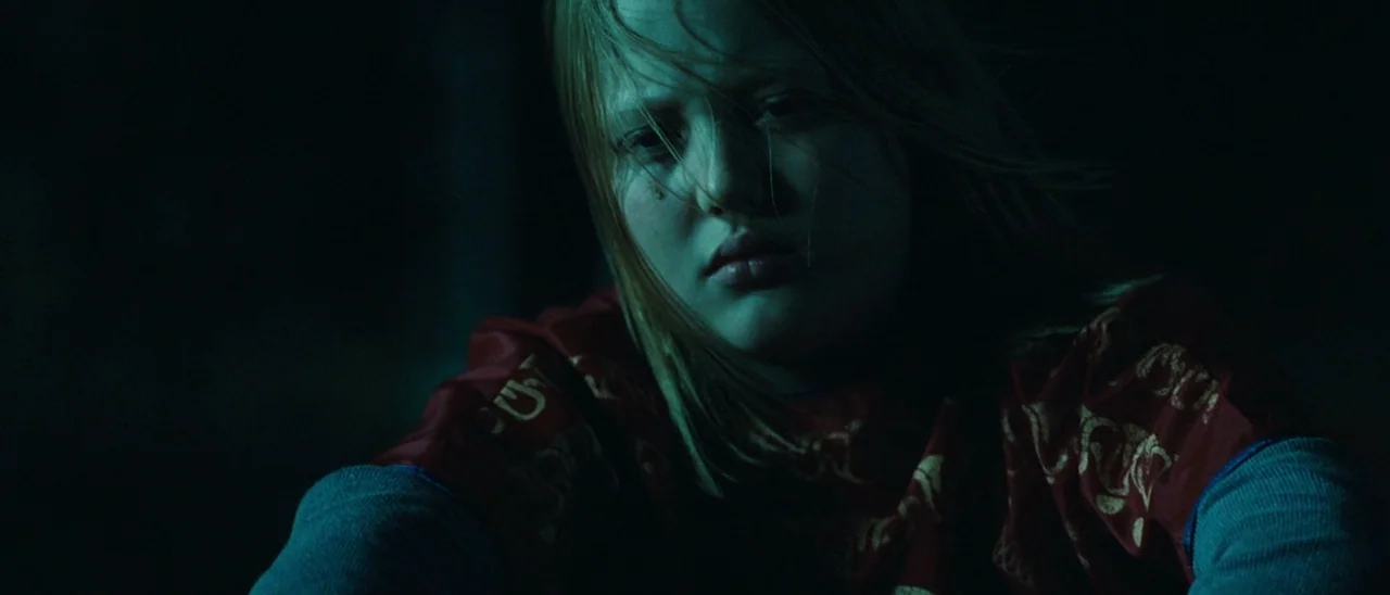 Halloween (2007) movie still: closeup — A dimly lit room provides no background detail, leaving the space obscured in shadows. A young woman with…