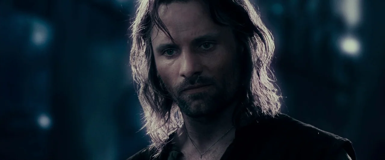 The Lord of the Rings: The Fellowship of the Ring (2001) movie still: closeup — A man stands in a dark, out-of-focus woodland area at night. He…
