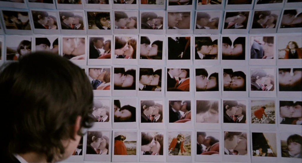 Submarine movie still: medium — A wall is completely covered in a dense grid of square white-bordered photographs. A person is seen from behind,…