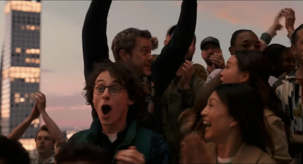 Karate Kid: Legends (2025) movie still: medium — A group of people watch an event from bleachers at golden hour. The crowd cheers with arms raised…