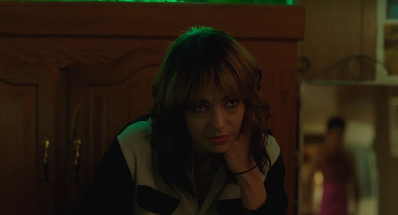 I Saw The TV Glow (2024) movie still: medium — An interior apartment space features a large aquarium with glowing green water against a wall. A…