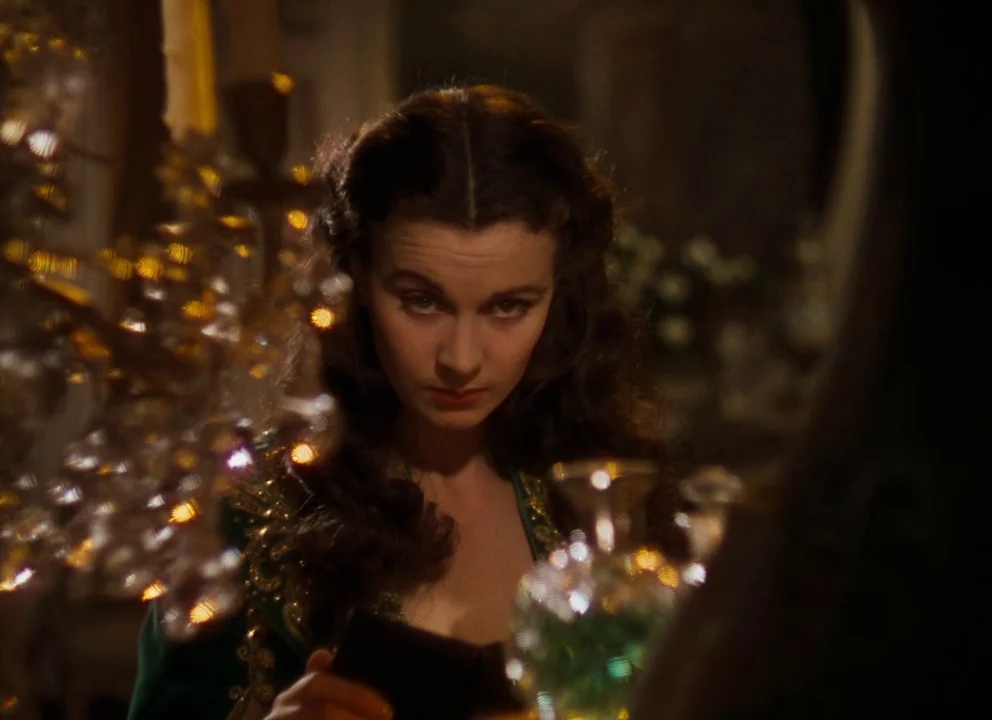Gone with the Wind (1939) movie still: closeup — A dimly lit room focuses on a woman reflected in a vanity mirror. Crystal decanters and glassware…