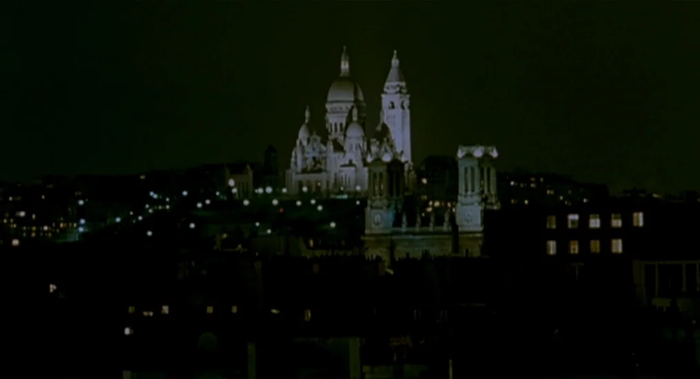 Vendredi Soir (2002) movie still: establishing — A night view of a distant white basilica structure illuminated atop a dark hillside. Multiple city…