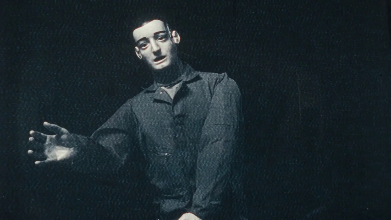 Once Within A Time (2022) movie still: medium — A man stands against a dark, featureless background with heavy video interference lines. He extends…