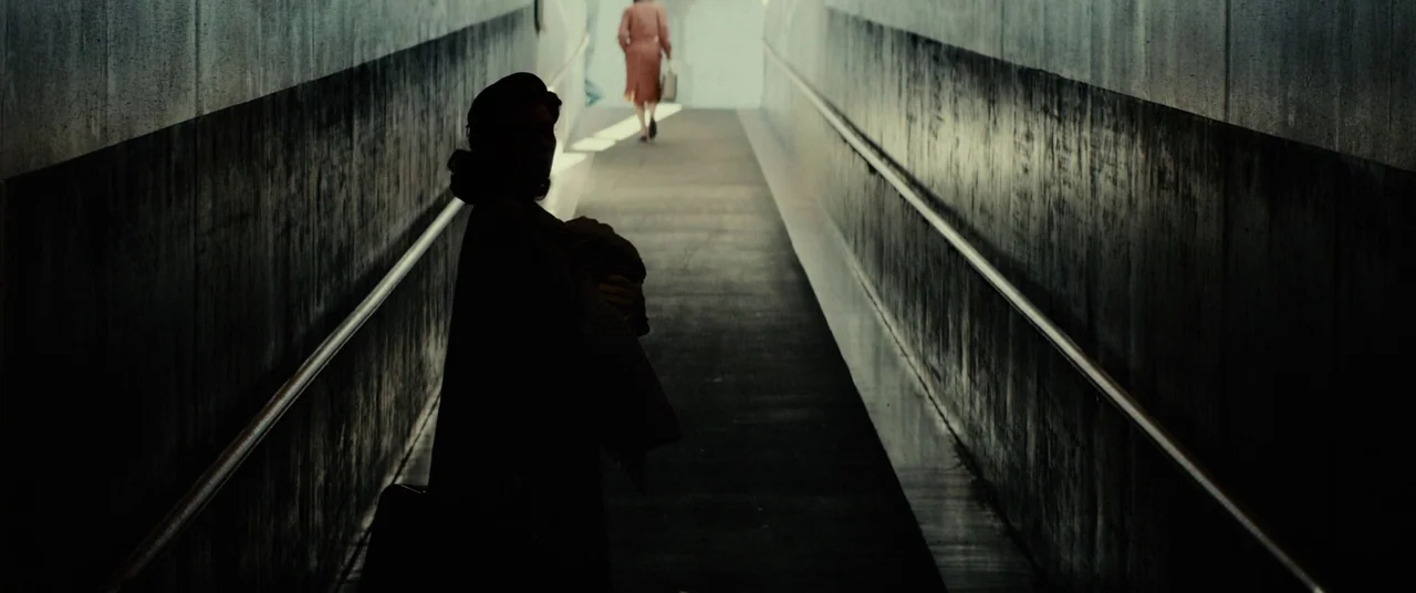 Gangster Squad (2013) movie still: medium — A concrete pedestrian ramp leads toward a bright opening in the distance. A woman in silhouette stands…