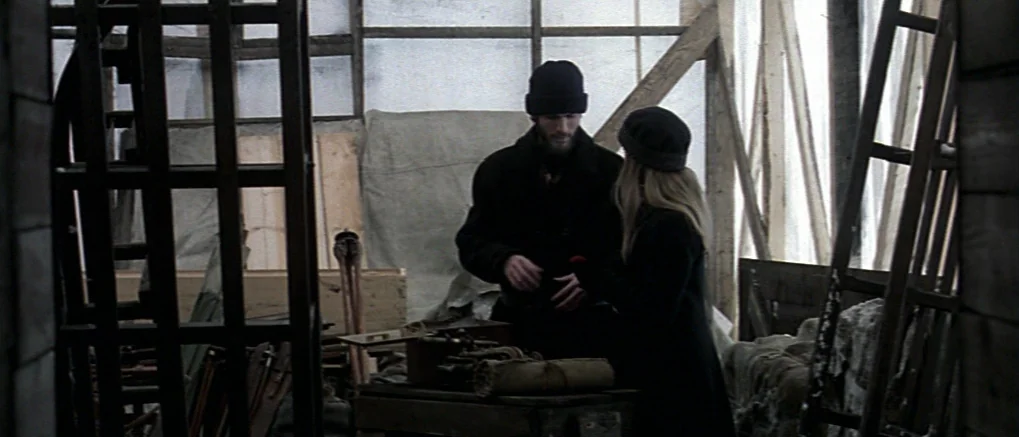 The Claim (2000) movie still: medium — A cluttered workshop filled with wooden ladders, tarp, and miscellaneous tools under translucent sheeting. A…