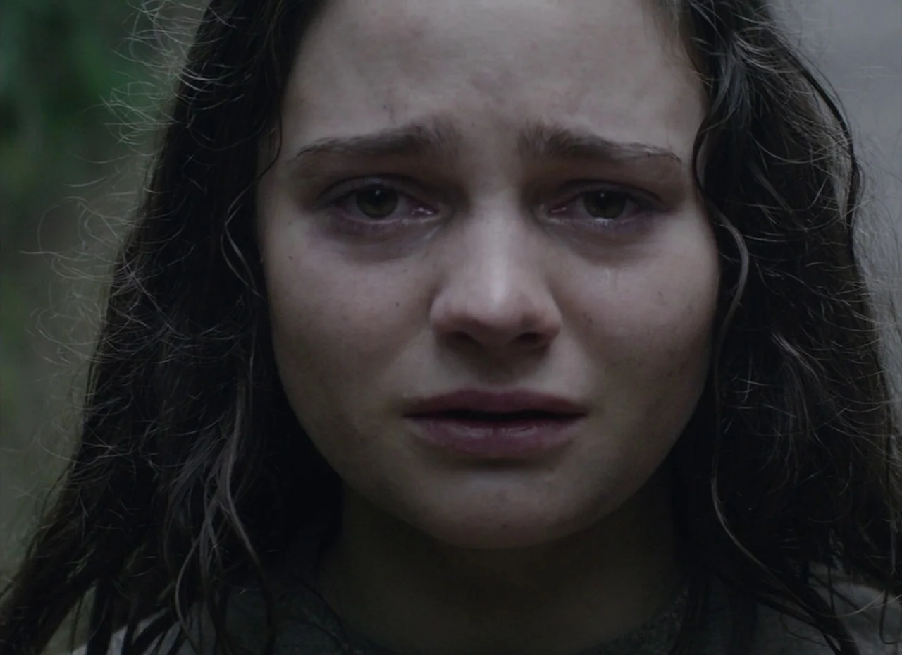 The Nightingale (2018) movie still: closeup — An outdoor area with soft ambient light providing even illumination on the face. A young woman with…
