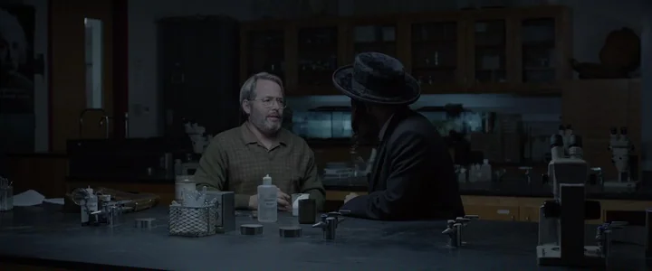 To Dust - Nightmares (2018) movie still: medium — A dimly lit science laboratory contains wooden cabinets and black-topped tables with scientific…