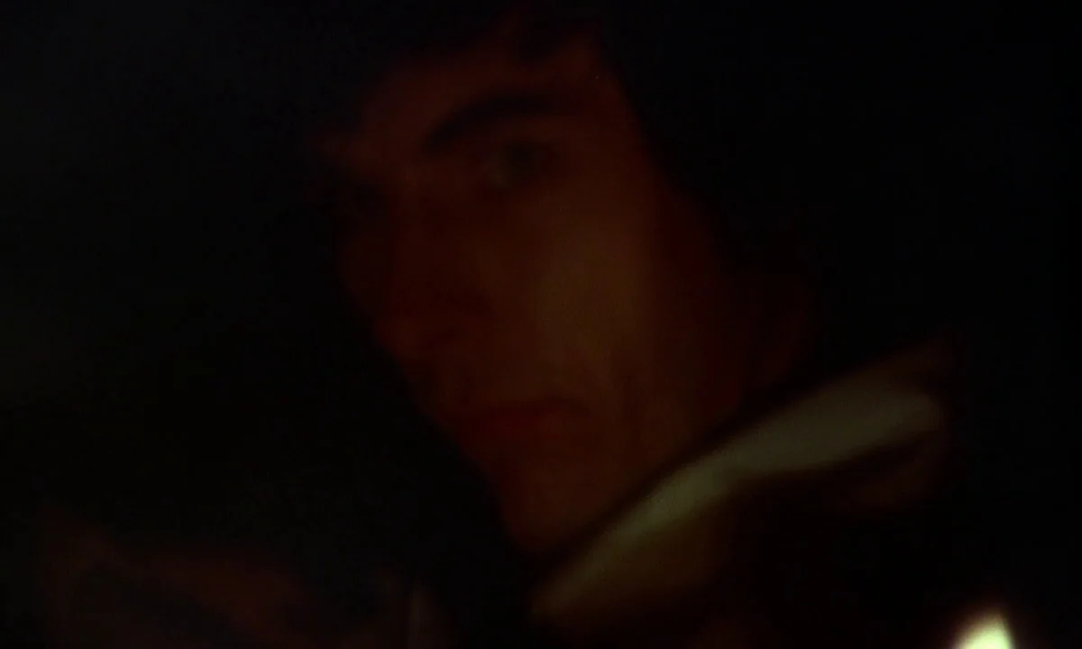 Vampire Circus (1972) movie still: closeup — A very dark, indistinct interior setting obscured by heavy shadows. A man's face is partially…