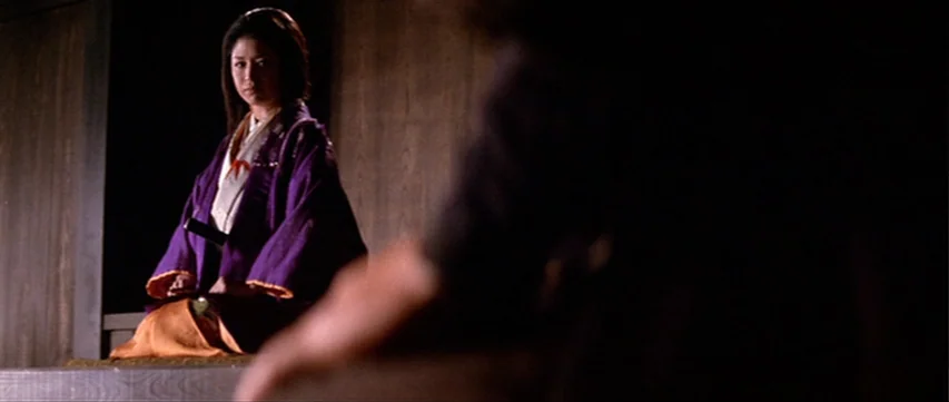 Lone Wolf: Baby Cart at the River Styx (1972) movie still: medium — A dimly lit room features a woman seated on a raised wooden platform. She waits…
