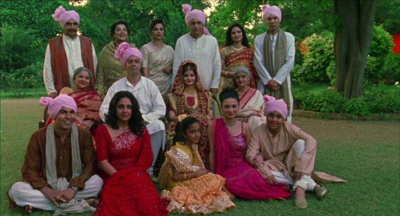 Monsoon Wedding (2001) movie still: wide — A large extended family poses together in a green park during the daytime. The members are arranged in…