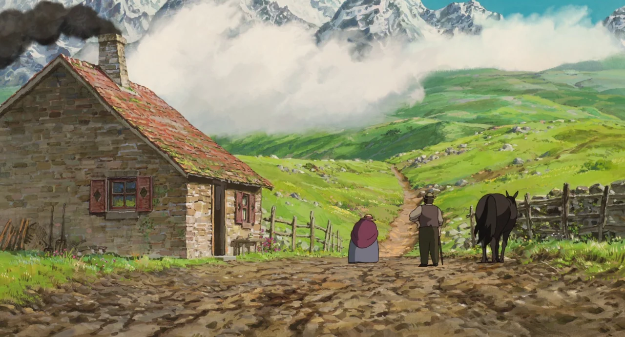 Howl’s Moving Castle (2004) movie still: wide — A stone cottage with a chimney stands beside a dirt path leading toward mountains. A woman, a man,…