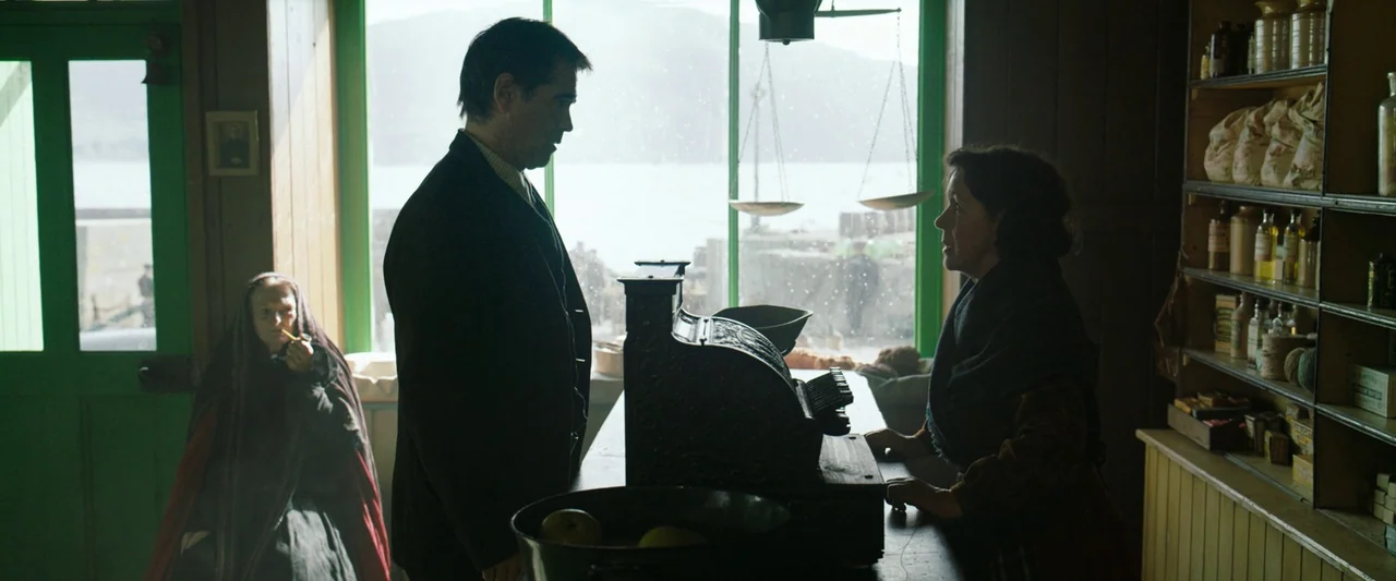 The Banshees of Inisherin (2022) movie still: medium — A rural wooden general store features a counter with a vintage cash register. A man stands at…