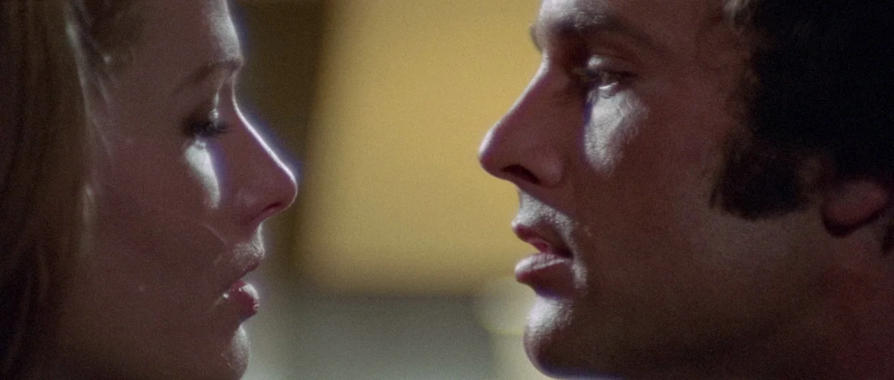 The Case of the Scorpion’s Tail (1971) movie still: closeup — Two individuals face each other in a dimly lit, blurred indoor space. A man and a…