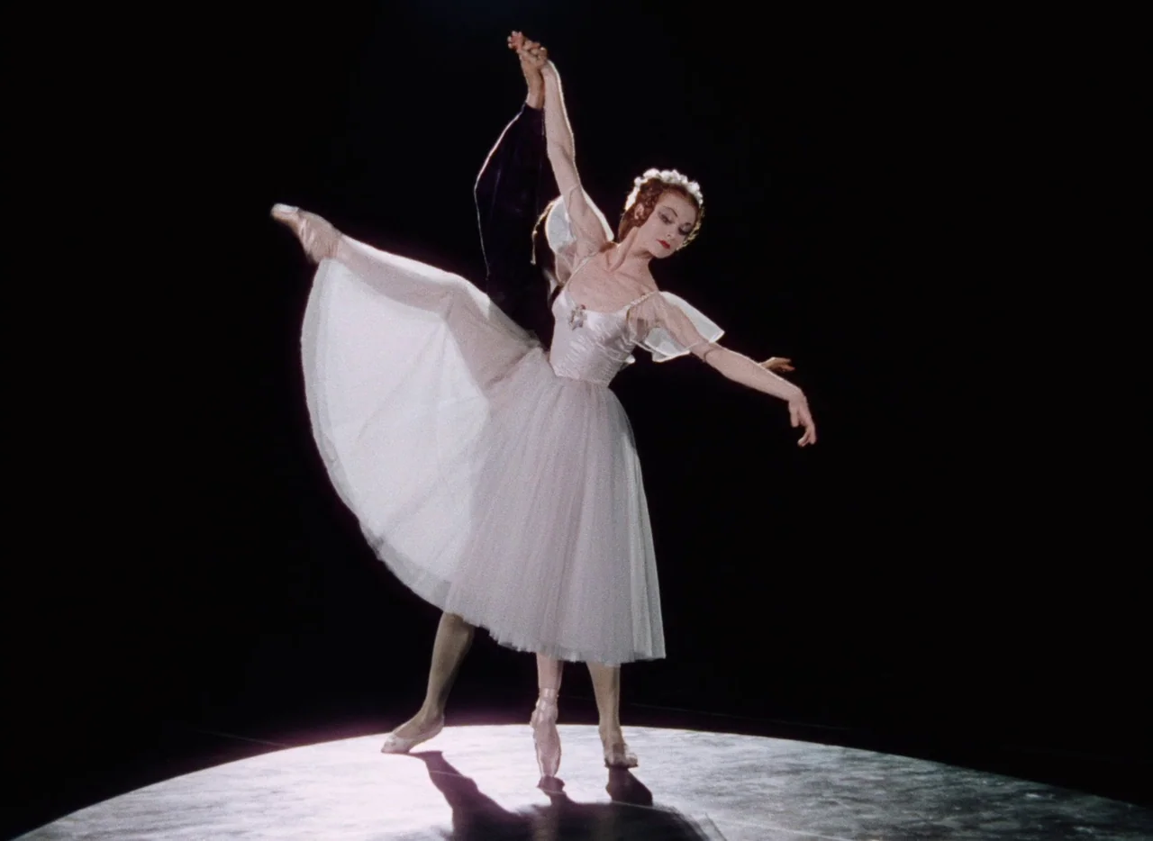 The Tales of Hoffmann (1951) movie still: fullbody — A dark stage illuminated by a singular circular spotlight from above. A female ballerina in a…