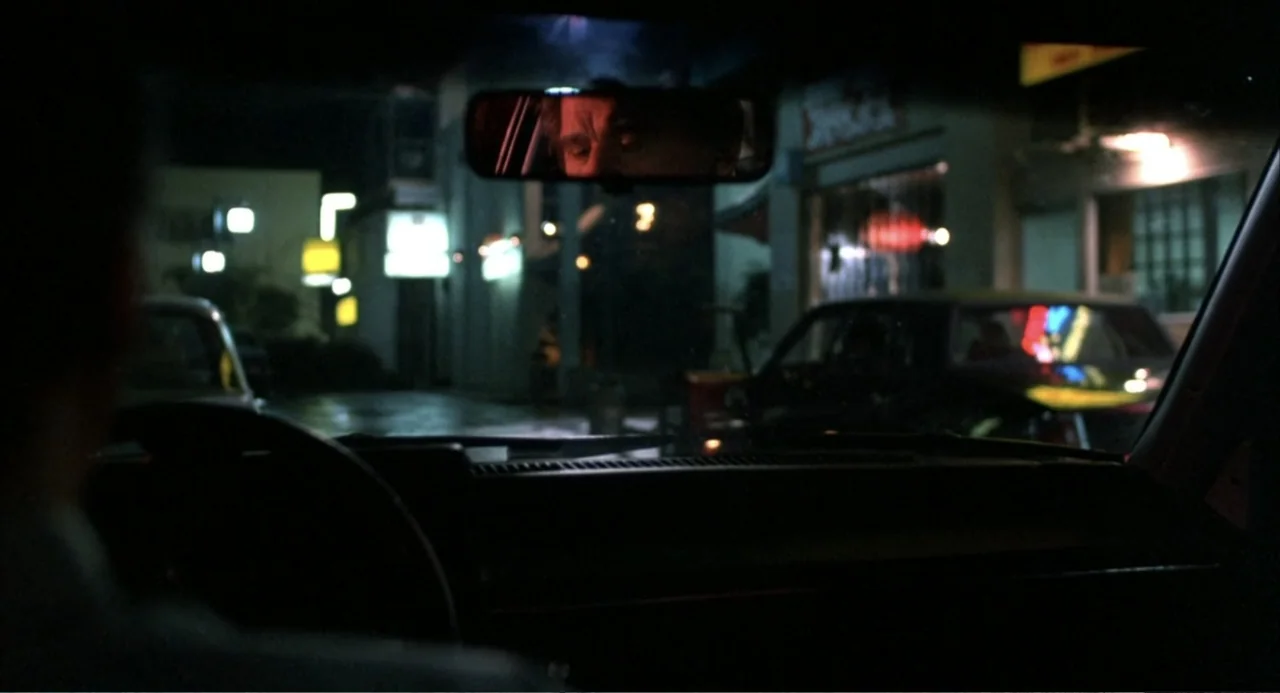 Murphy's Law (2009) movie still: medium — A dark car interior at night framed from the perspective of the driver. A person's face is reflected in…