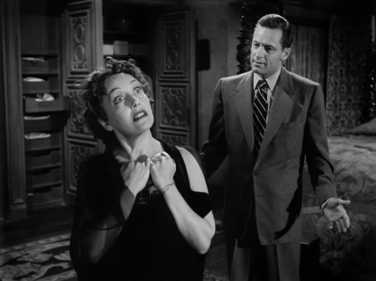 Sunset Boulevard (1950) movie still: medium — A dark, wood-paneled dressing room features open storage cabinets and a plush draped bed. A woman in a…