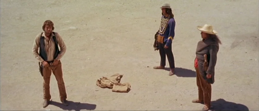 Django Kill (1967) movie still: wide — Three men stand on a vast, flat expanse of sun-baked desert sand. They are positioned in a triangular…