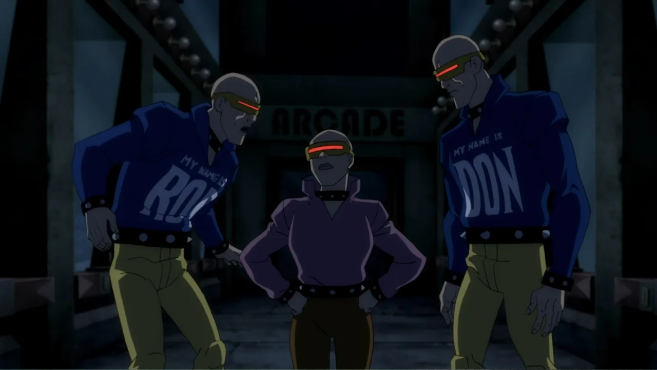 Batman: The Dark Knight Returns, Part 1 (2012) movie still: fullbody — Three bald individuals with red visors stand before an arcade entrance at…