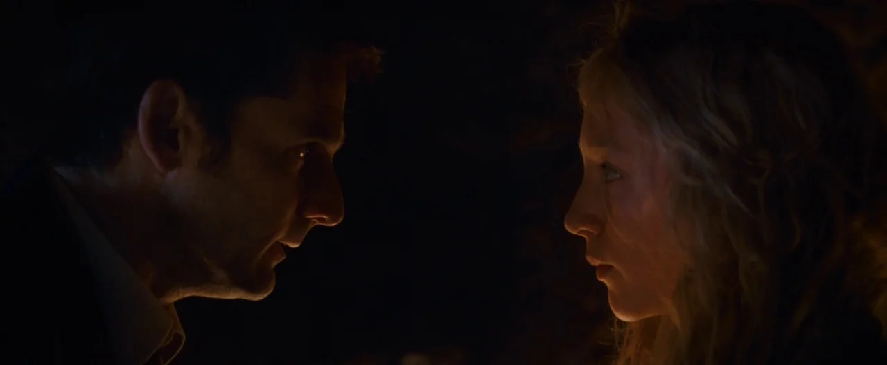 Hanna (2011) movie still: medium — A dimly lit interior space is completely obscured by darkness except for two figures. A man and a young woman…