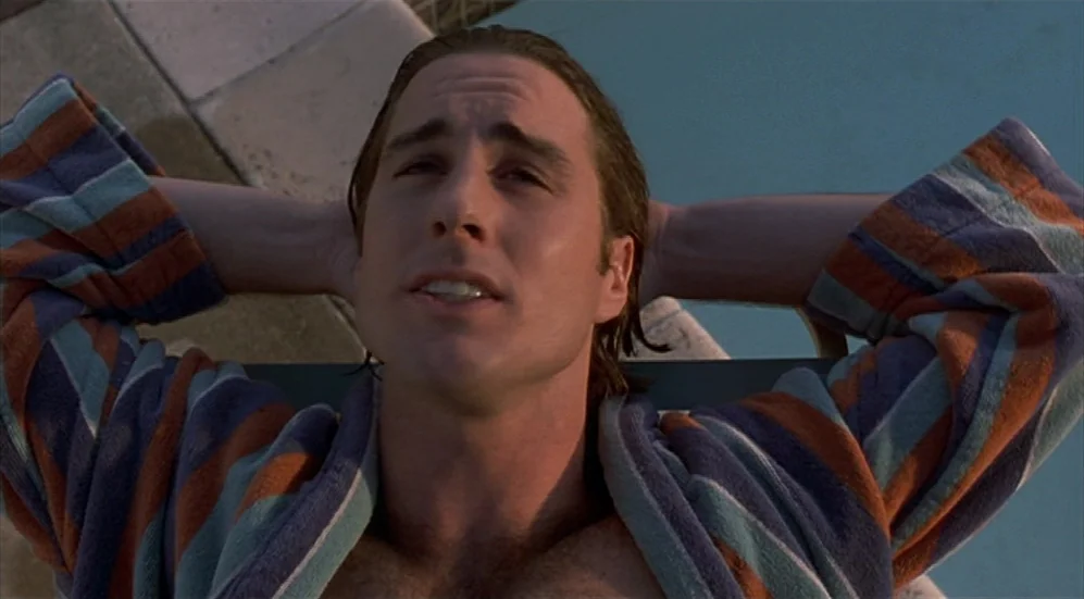 Bottle Rocket (1996) movie still: closeup — A man lies on a lounge chair beside a clear blue swimming pool. He rests with his arms folded behind his…