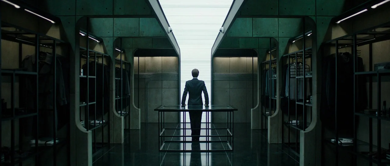 Predestination (2014) movie still: wide — A symmetrical high-end dressing space features custom dark metal shelving and concrete panels. A lone man…