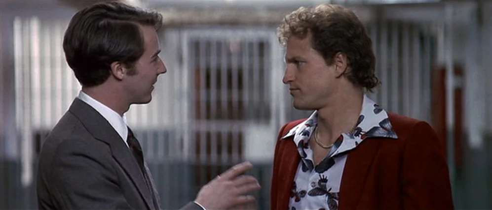 The People vs. Larry Flint (1996) movie still: medium — A sterile institutional space features a metal grid divider behind the two men. Two men in…