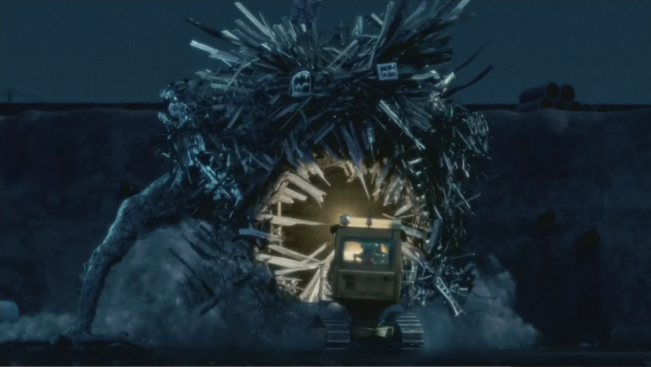 Monster House (2006) movie still: wide — A large chaotic sculpture made of splintered wooden boards and debris stands at night. A yellow bulldozer…