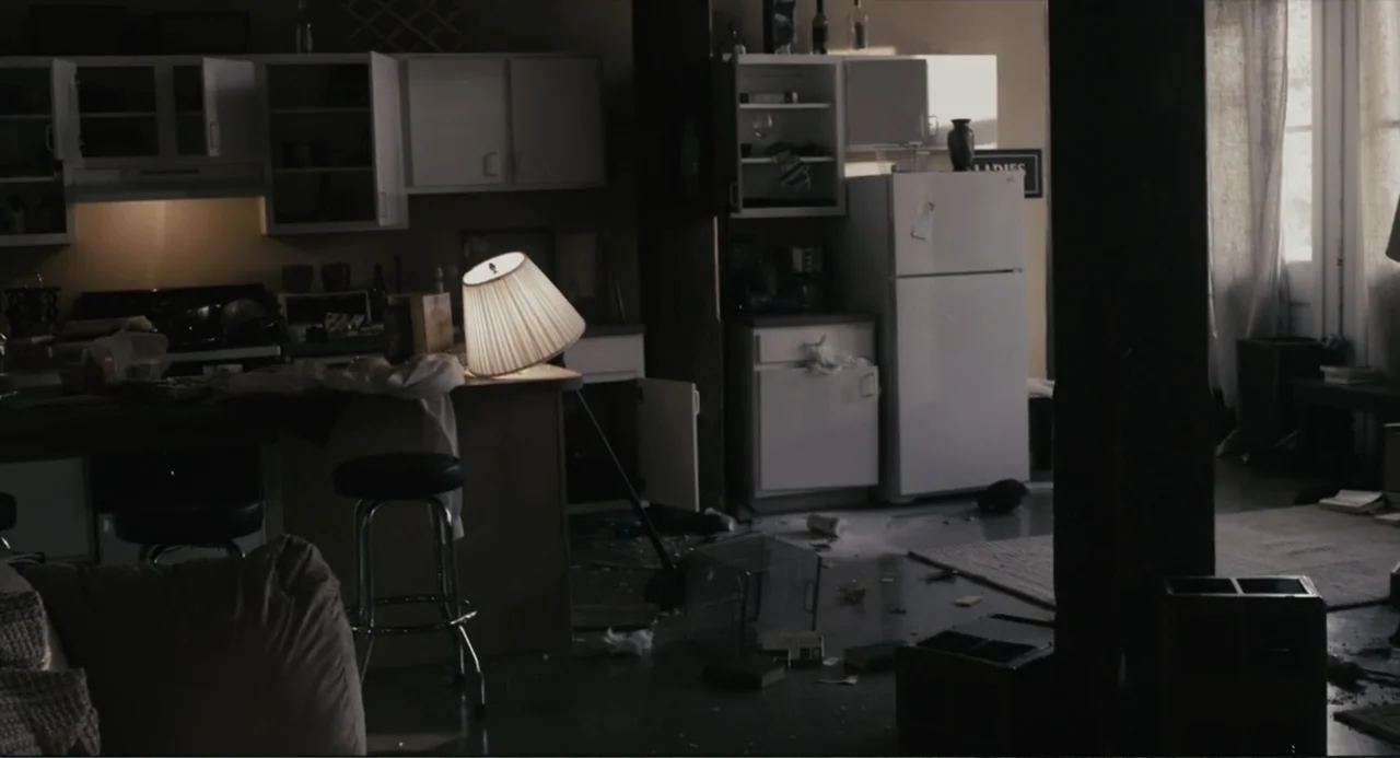 Beyond a Reasonable Doubt (2009) movie still: wide — An untidy apartment living area features a white refrigerator and a fallen floor lamp. Debris…