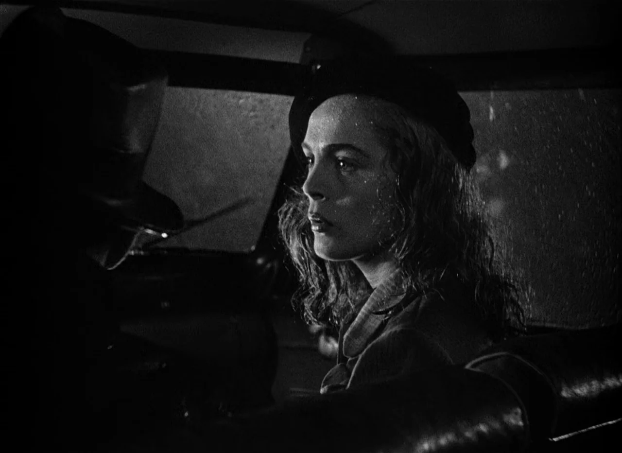 Dead Reckoning (1946) movie still: medium — A dark car interior at night showing a woman in a beret. She sits in the passenger seat looking toward a…