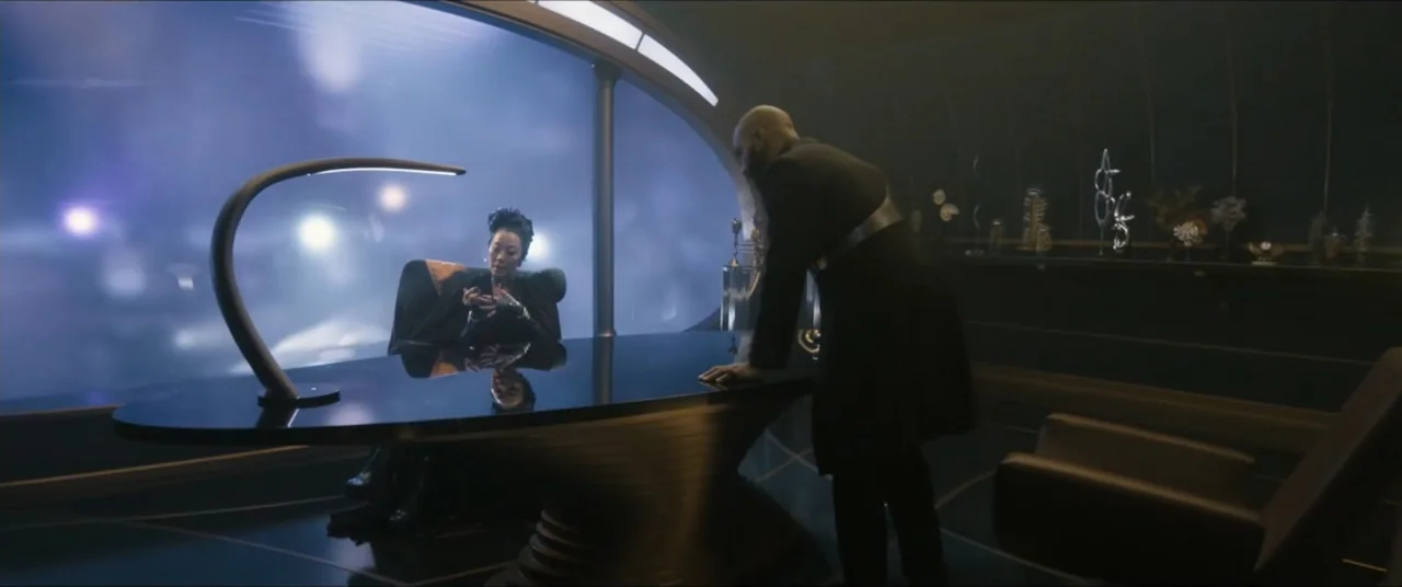 Star Trek: Section 31 (2025) movie still: wide — A dark, modern interior features a large desk and a panoramic curved window view. Two individuals…
