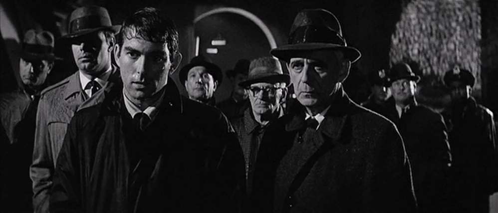 In Cold Blood (1967) movie still: medium — A group of men in fedoras and coats stand together on a dark street. They look ahead with serious…