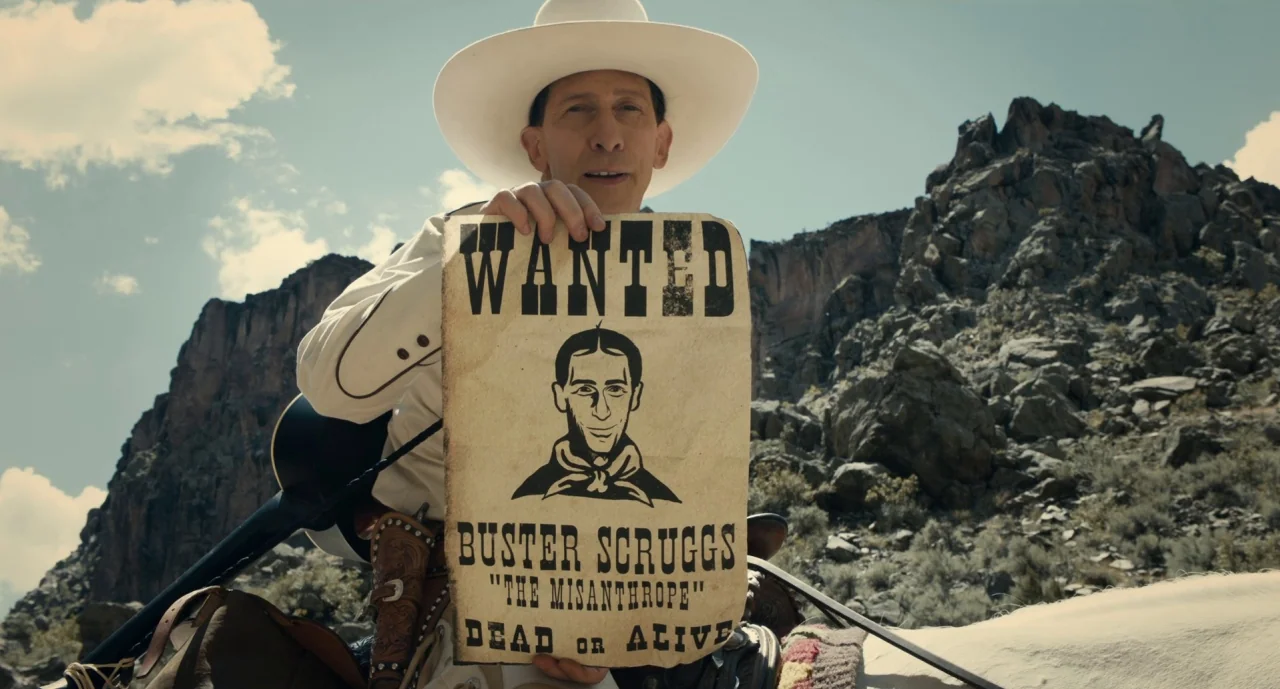 The Ballad of Buster Scruggs (2018) movie still: medium — A rugged canyon landscape with towering rock cliffs under a clear blue sky. A man in a…