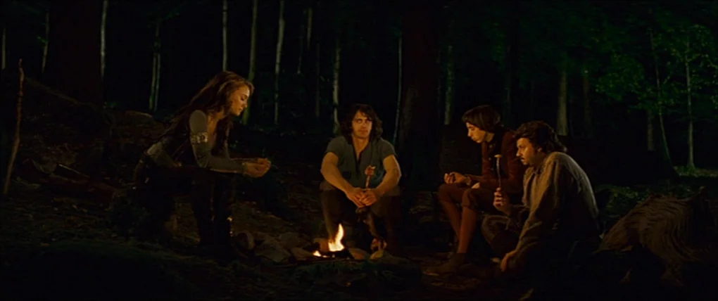 Your Highness (2011) movie still: wide — A dark, dense woodland clearing features four figures seated around a small crackling campfire. The fire…