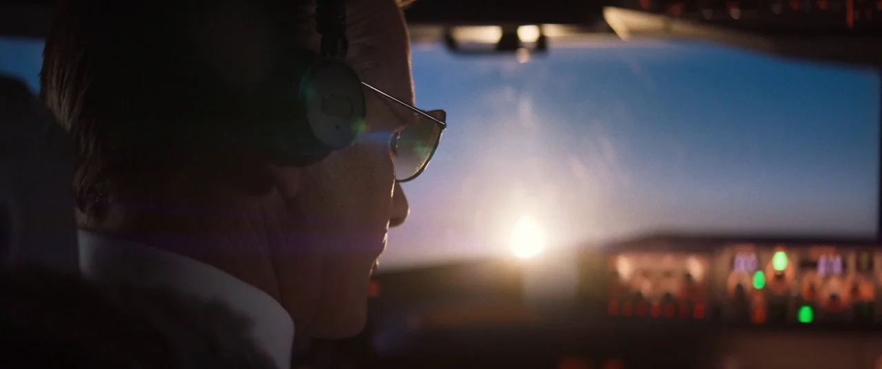 Falling (2020) movie still: closeup — A close-up view from inside an airplane cockpit looking out through the front window. A man in profile wears…