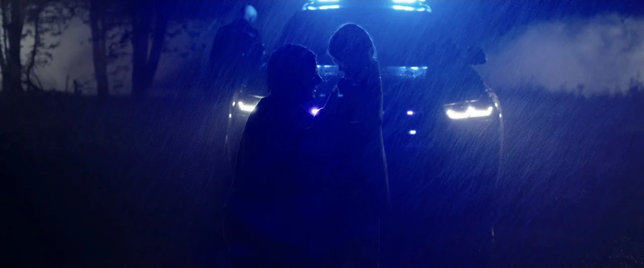 Winnie-the-Pooh: Blood and Honey 2 (2024) movie still: medium — A dark outdoor scene at night features heavy rain illuminated by bright blue lights.…