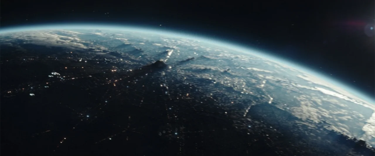 Moonfall (2022) movie still: establishing — A view from space shows the curvature of the earth with a glowing atmospheric rim. Nighttime city lights…