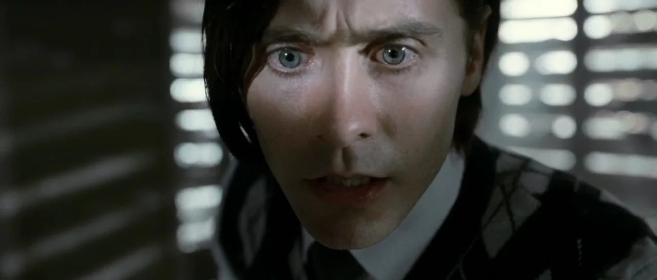 Mr. Nobody (2009) movie still: closeup — A dimly lit room with light filtering through horizontal blinds. A man looks directly into the lens with a…