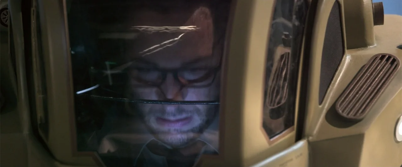 Office Uprising (2018) movie still: closeup — A close view inside a cockpit with metal surroundings and clear glass panels. A man wearing glasses…