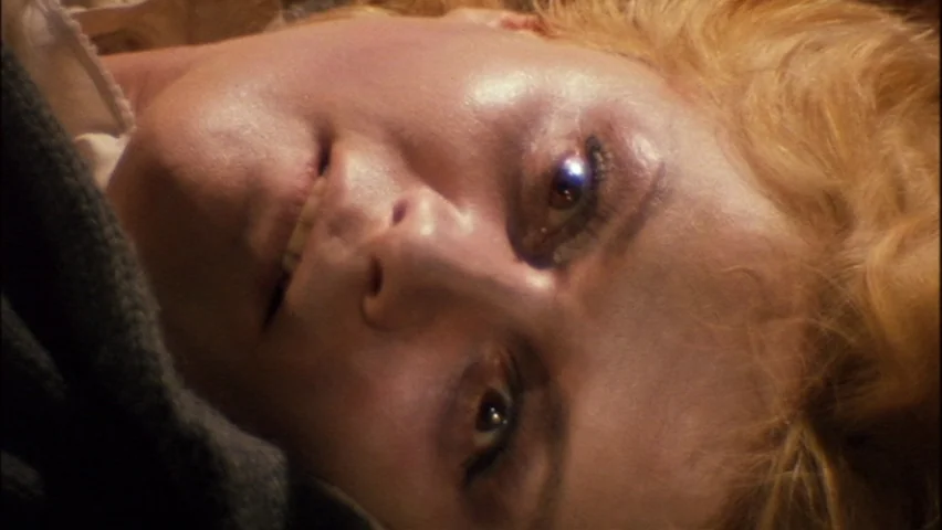 Black Sabbath (1963) movie still: closeup — A close-up view shows a person resting against a soft, dark fabric surface. The subject looks upward…